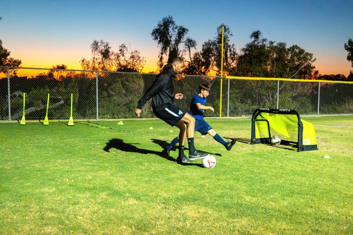 Coach Luka shielding the ball from a young player at sunset, The Soccer Lab, Carlsbad